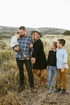 a family standing in a field holding their son's hand and smiling at the camera