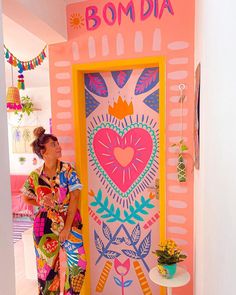 a woman standing in front of a colorful door with the word bomba painted on it