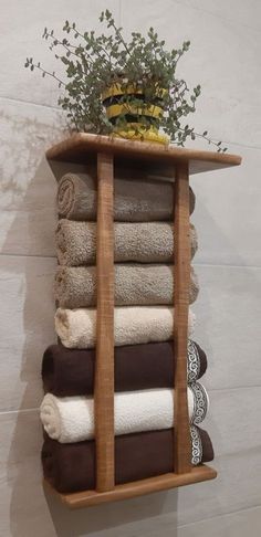 a wooden shelf filled with lots of folded towels and a potted plant on top