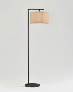 a black floor lamp with a beige shade