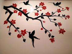 a painting of birds on a tree branch with red flowers painted on the wall behind it