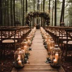 an outdoor wedding setup with candles and greenery on the aisle, surrounded by wooden chairs