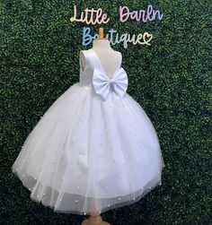 Our enchanting Ankle Length flower girl dresses are sure to turn heads! This beautiful elegant sophisticated dress is handmade, the bodice consists of White Bridal Satin with a sowed in sash at the waist, the back of the dress consists of an open V-back with a hidden zipper. The big bow is detachable. The skirt consists of 4 layers of tulle with the top layer consisting with sowed in pearl beads. The fifth layer is made of lining with crinoline for fullness.  This dress is perfect for any occasi Elegant Tutu Dress With Satin Bow For Weddings, Elegant Sleeveless Tutu Dress For First Communion, Elegant Tutu Wedding Dress With Satin Bow, Elegant Wedding Tutu Dress With Satin Bow, Elegant Tutu Dress With Satin Bow For Baptism, Fitted Princess Dress With Satin Bow For First Communion, Elegant White Tutu Dress For Confirmation, First Communion Princess Dress With Satin Bow, Tulle Baptism Dress With Satin Bow For First Communion