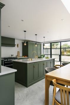 a kitchen with green cabinets and white counter tops, along with a dining room table