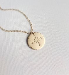 "14k gold fill Compass Necklace. ➳All metal is genuine 14k gold fill - chain, clasp and pendant. ➳Hand stamped Compass Symbol with hammered edge and brushed finish ➳Closure is a 14k gold fill lobster clasp with crystal pearl beads. \"Not all who wander are lost.\" \"Choose your own adventure.\" \"She believed she could, so she did.\" \"Enjoy the journey, wherever it may take you.\" \"Go confidently in the direction of your dreams.\" Whether graduating and moving on or traveling to a far away lan Gold Stamped Sterling Silver Charm Necklaces, Stamped Gold Charm Necklaces In Sterling Silver, Gold Sterling Silver Stamped Charm Necklaces, Sterling Silver Gold Necklace With Compass Design, Gold Brass Jewelry With Compass Design, Gold Stamped Pendant Charm Necklace, Engraved Round Pendant Jewelry For Everyday Use, Gold Stamped Round Pendant Necklace, Everyday Engraved Round Pendant Jewelry