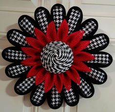 a black and white wreath with a red flower on it's front door hanger