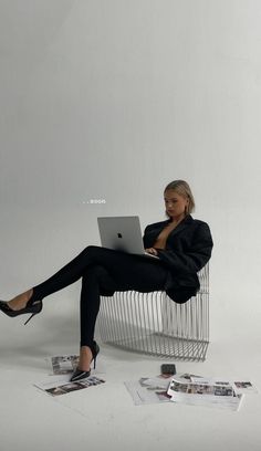 a woman sitting in a chair with her legs crossed on the floor while using a laptop