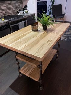 a kitchen island made out of wooden planks and pipe legs with a potted plant on top