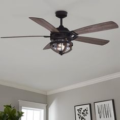 a ceiling fan in a living room with pictures on the wall