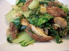 a white plate topped with broccoli, mushrooms and other food items on top of it