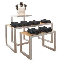 three tables with folded black shirts on them