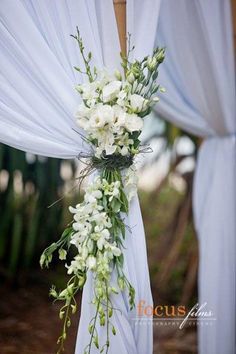 an image of a wedding ceremony with flowers on the back of the aisle and white draping