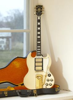 an electric guitar and case sitting on a window sill