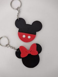 two mickey mouse keychains with red and black bows on them, one in the shape of a head