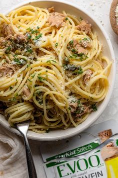 a bowl of pasta with meat and parmesan cheese on the side next to some crackers