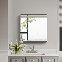 a bathroom with a sink, mirror and flowers on the counter in front of it