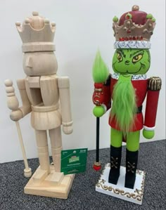 two wooden nutcrackers are on display in an office cubicle, one is wearing a green costume and the other has a crown