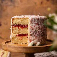 a piece of cake with white frosting and raspberry toppings on a wooden plate