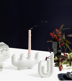 a white candle holder sitting on top of a table next to a vase with flowers