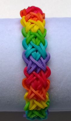 rainbow colored bracelets are stacked on top of each other, with one knot at the end