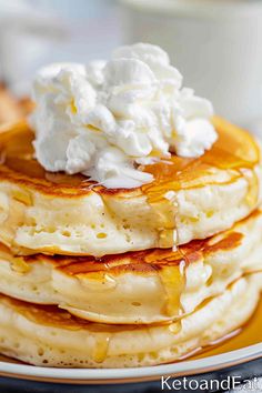 stack of pancakes topped with whipped cream and syrup