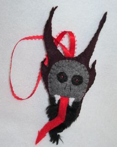 a small stuffed animal with a red ribbon around it's neck and eyes hanging from a string