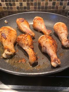 chicken legs are cooking in a pan on the stove