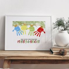 a christmas card with three handprints hanging from a tree branch on a shelf