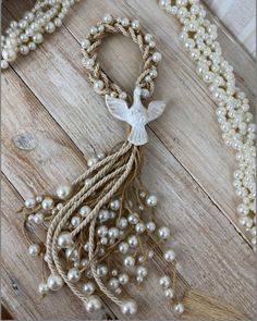 a necklace with pearls and an angel on it, sitting on a wooden floor next to other beads