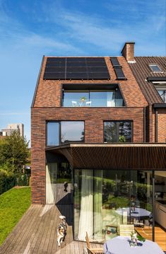 a house with a wooden deck and lots of windows on the top floor is surrounded by grass