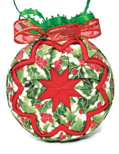 a christmas ball ornament with holly and red ribbon on it's top