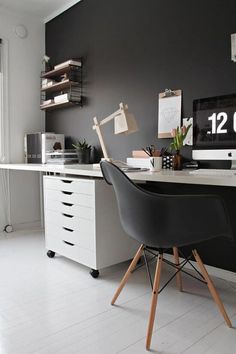 a desk with a computer on top of it in front of a wall mounted clock