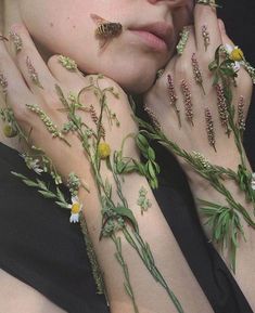 a woman with her hands on her face and flowers all over her body, both covered in green leaves