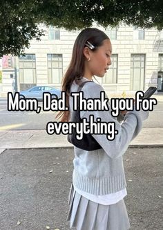 a girl is standing in the street with her hand on her hip and texting mom,