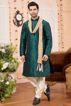 Create an extraordinary style statement by wearing this readymade teal green art silk men's kurta churidar and woven zari dark beige silk dupatta. It also features a Chinese collar neck and full sleeves. Accompanied by a beige-colored art silk bottom. This kurta churidar can be customized up to a maximum size of 46 inches. Slight color variation may occur due to photographic reasons. Velvet Suit Design, Anarkali Suits Bollywood, Frock Style, Green Plain, Men's Kurta, Kurta Men, Bollywood Dress, Orange Saree, Purple Saree