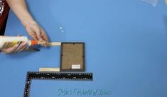 a person is using a ruler to measure the width of a piece of paper on a blue surface