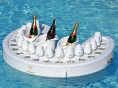 two bottles of champagne are placed in the bottom of a pool with cups on it