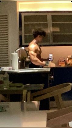 a shirtless man is cooking in the kitchen