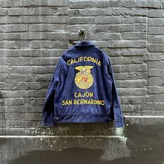 a denim jacket hanging on the side of a brick wall that says california cajon san bernarono