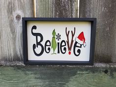 a framed sign that says believe with elf hats and snowflakes on the bottom