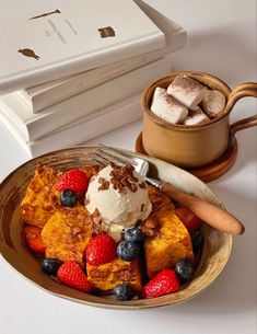 a plate topped with french toast covered in berries and ice cream next to a cup of coffee