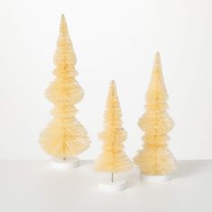 three yellow christmas trees on white pedestals