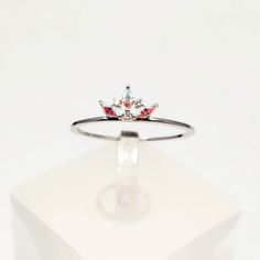 a ring with three stones on it sitting on top of a white cubed box