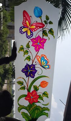 a painting on the side of a building with flowers and butterflies painted on it