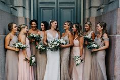 a group of women standing next to each other in front of a building holding bouquets