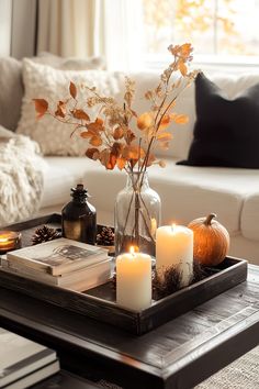 a tray with candles and flowers in it on a coffee table next to a couch