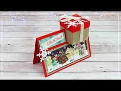 a card with a gift box on top of it, and the words merry christmas written in