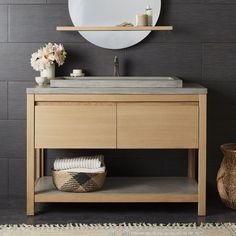 a bathroom vanity with a round mirror above it and a basket on the floor next to it