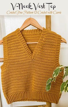 an orange knitted sweater sitting on top of a wooden chair next to a potted plant