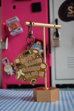 a keychain with a game controller attached to it sitting on a table in front of a pink refrigerator